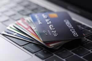 Éventail de cartes de crédit prépayées sur un clavier d'ordinateur, évoquant leurs avantages et risques.