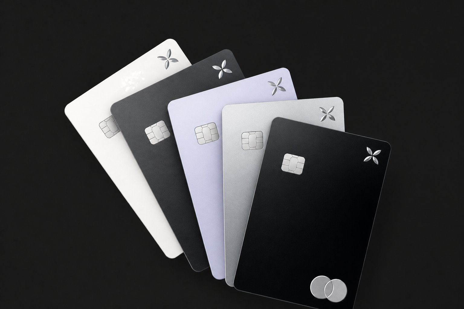 Cinq cartes bancaires Qonto de différentes couleurs disposées en éventail sur un fond noir.